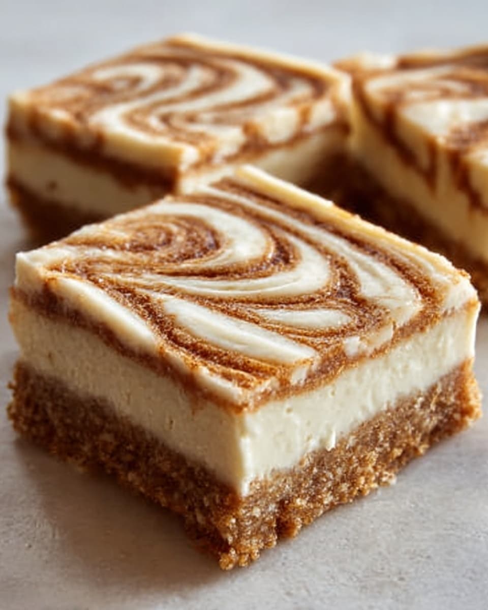 The image shows two square pieces of dessert with three visible layers. The bottom layer is a crumbly brown base that looks like crushed nuts or biscuit crumbs. The middle layer is thick, cream-colored, and smooth, appearing soft and custard-like. The top layer is light brown with a white icing swirl pattern, giving it a textured and slightly glossy look. The dessert pieces are placed closely together on a white marbled surface. Photo taken with an iphone --ar 4:5 --v 7