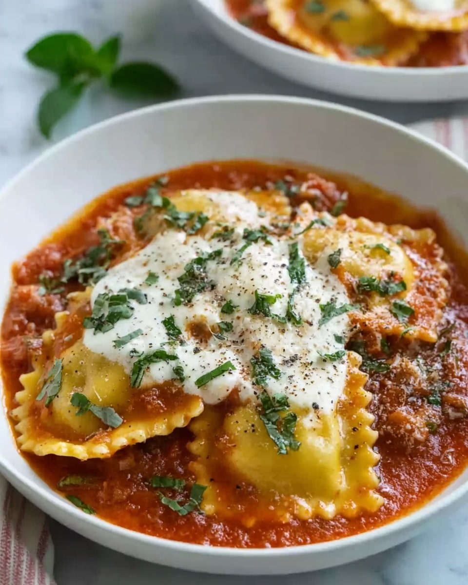 A white bowl filled with several layers of ravioli covered with a thick red tomato sauce and sprinkled with chopped green herbs. The ravioli are golden yellow with slightly ruffled edges, sitting in a shallow pool of sauce. On top, there is a white melted cheese layer, creamy and smooth, sprinkled with more herbs and a light dusting of black pepper. The bowl is placed on a white marbled surface with some green leaves around. Photo taken with an iphone --ar 4:5 --v 7