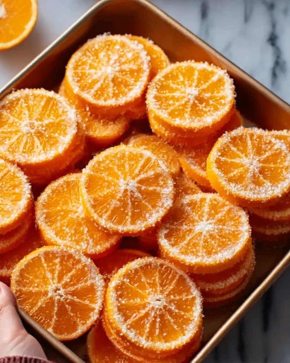 The image shows a tray filled with multiple round orange slices, each slice topped with a thin layer of white sugar crystals that add a sparkly texture. The orange slices are stacked in single layers on the tray, revealing the juicy and bright orange flesh with visible segments. A woman's hand is holding the tray from the side, and the background is a white marbled texture. photo taken with an iphone --ar 4:5 --v 7