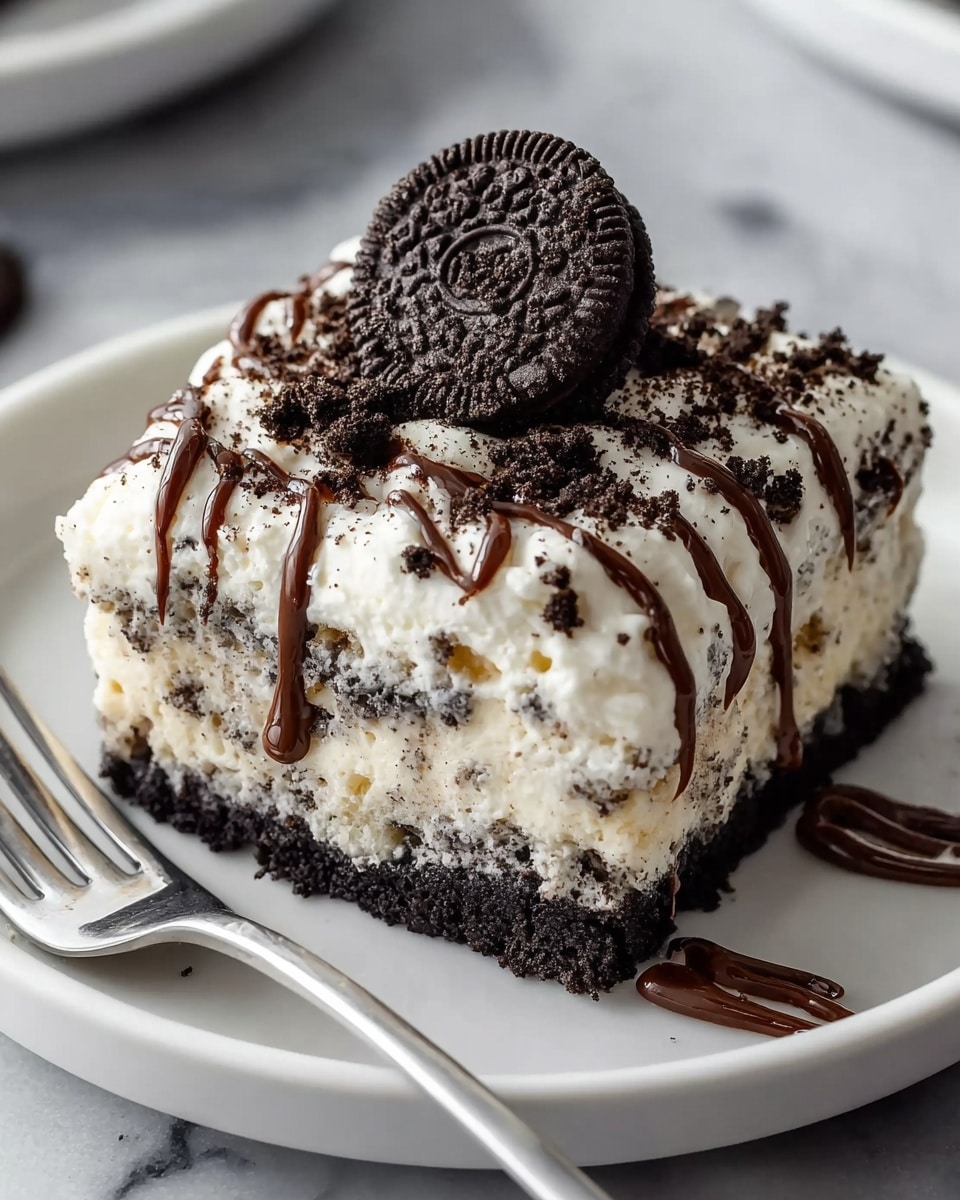The image shows a thick square slice of Oreo cream dessert on a white plate. The bottom layer is a dark, crumbly Oreo crust. Above this is a white, creamy layer mixed with crushed Oreo pieces giving it a speckled look. The top layer is fluffy white cream with Oreo crumbs scattered on top. There are several thin lines of chocolate drizzle running down the sides and top of the dessert. A whole Oreo cookie sits on the top center as decoration. The plate rests on a white marbled surface, next to a silver fork. Photo taken with an iphone --ar 4:5 --v 7