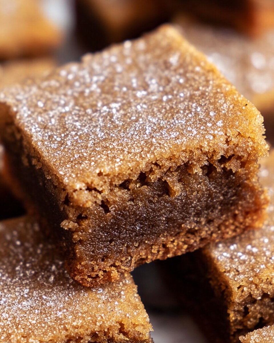 A close-up of two stacked brown sugar blondie squares showing a crumbly, moist texture. The top layer is a light golden brown with a sugar crystal coating, giving it a slightly crunchy look, while the bottom layer is a denser, darker brown. The edges are rough and crumbly, and the squares are tightly stacked, highlighting the soft and chewy inside. The background is softly blurred, emphasizing the detailed texture of the blondies. photo taken with an iphone --ar 4:5 --v 7