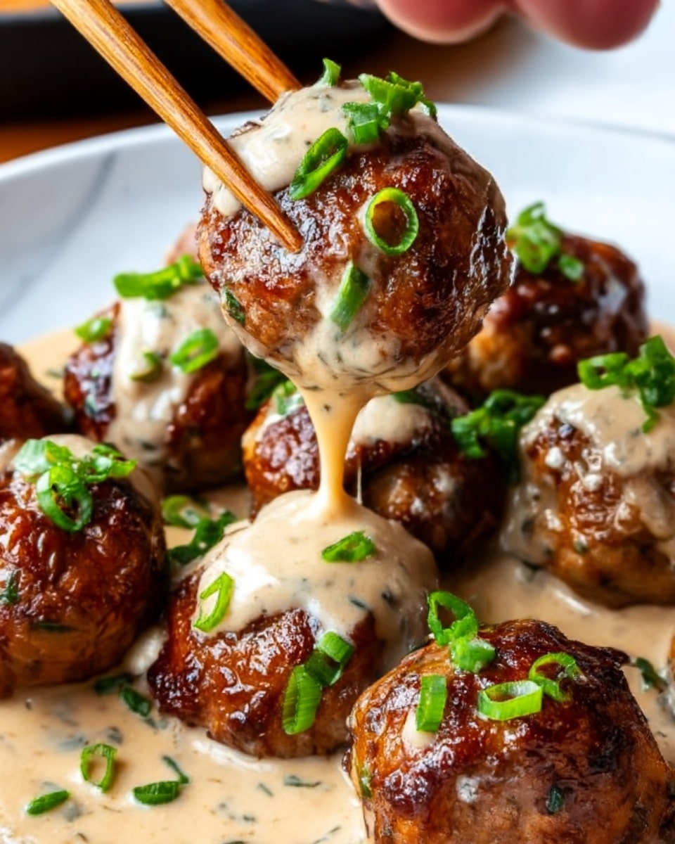 The image shows several browned meatballs covered in a creamy, light beige sauce with some herbs mixed in. The meatballs have a shiny, slightly sticky surface and are garnished with chopped green onions sprinkled on top. A woman's hand is using chopsticks to lift one meatball, causing the sauce to drip down towards the others. The background is a white marbled texture, enhancing the rich colors and textures of the dish. photo taken with an iphone --ar 4:5 --v 7