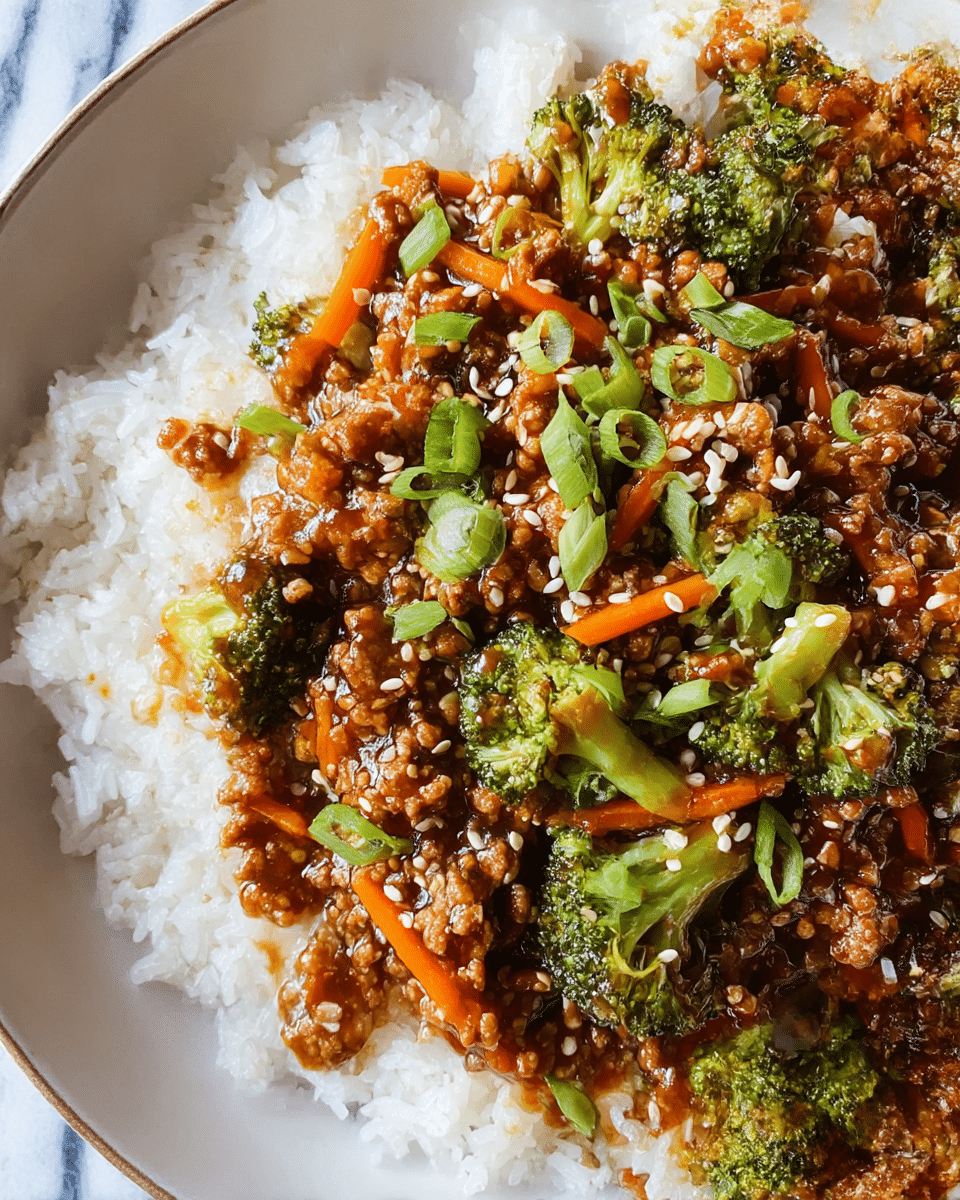 A white bowl filled with a base layer of soft, white rice grains appearing fluffy and slightly sticky. On top is a thick, chunky mixture of ground meat cooked in a glossy, dark brown sauce that glistens with a slight shine. Mixed throughout the meat are bright green broccoli florets, thin orange carrot strips, and small pieces of chopped green onions scattered on top, adding fresh vibrant green hues and a slight crunch. White sesame seeds are sprinkled over the dish, giving subtle light contrast. The bowl rests on a white marbled surface. photo taken with an iphone --ar 4:5 --v 7
