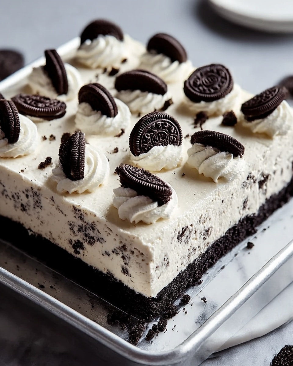 A square dessert with two main layers sits on a white marbled surface. The bottom layer is a dark, crumbly cookie crust, almost black in color, forming the base. The top layer is thick and creamy white with bits of dark cookie mixed inside, making a speckled pattern. On top, dollops of white whipped cream evenly cover the surface, each topped with a whole dark chocolate sandwich cookie, arranged in a grid pattern. The edges of the top cream layer are slightly rough and rustic-looking. The whole dessert is on a metal tray resting on the white marbled surface. photo taken with an iphone --ar 4:5 --v 7