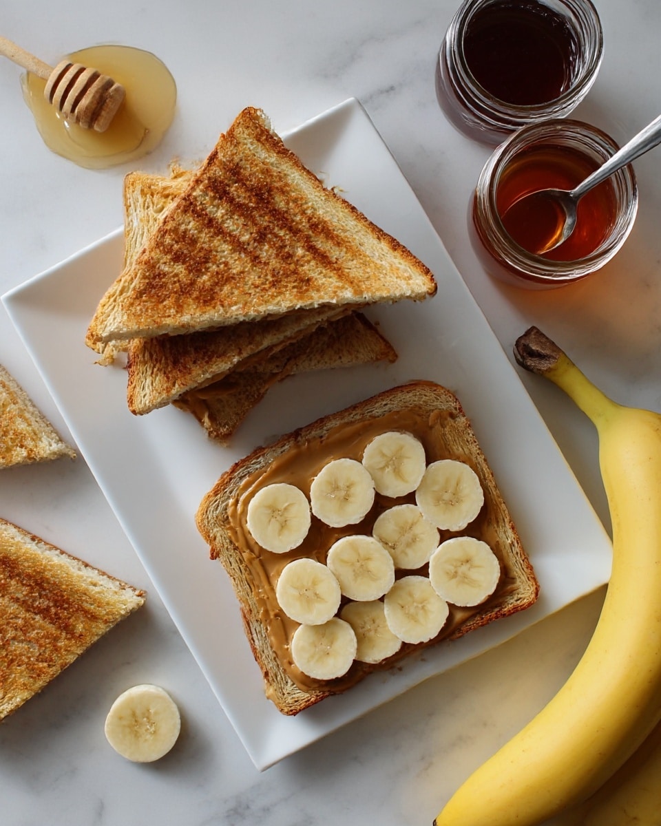 The image shows two toasted sandwich halves on a white square plate. One half is stacked with even, round banana slices on top of a creamy spread, showing two layers: golden-brown toast at the bottom and yellowish banana slices on top. The other half is a grilled sandwich with visible brown grill marks and a soft inner layer of nutty spread with bits visible inside. Around the plate, there are whole yellow bananas and two jars with dark syrup and honey. The scene is set on a white marbled surface. Photo taken with an iphone --ar 4:5 --v 7